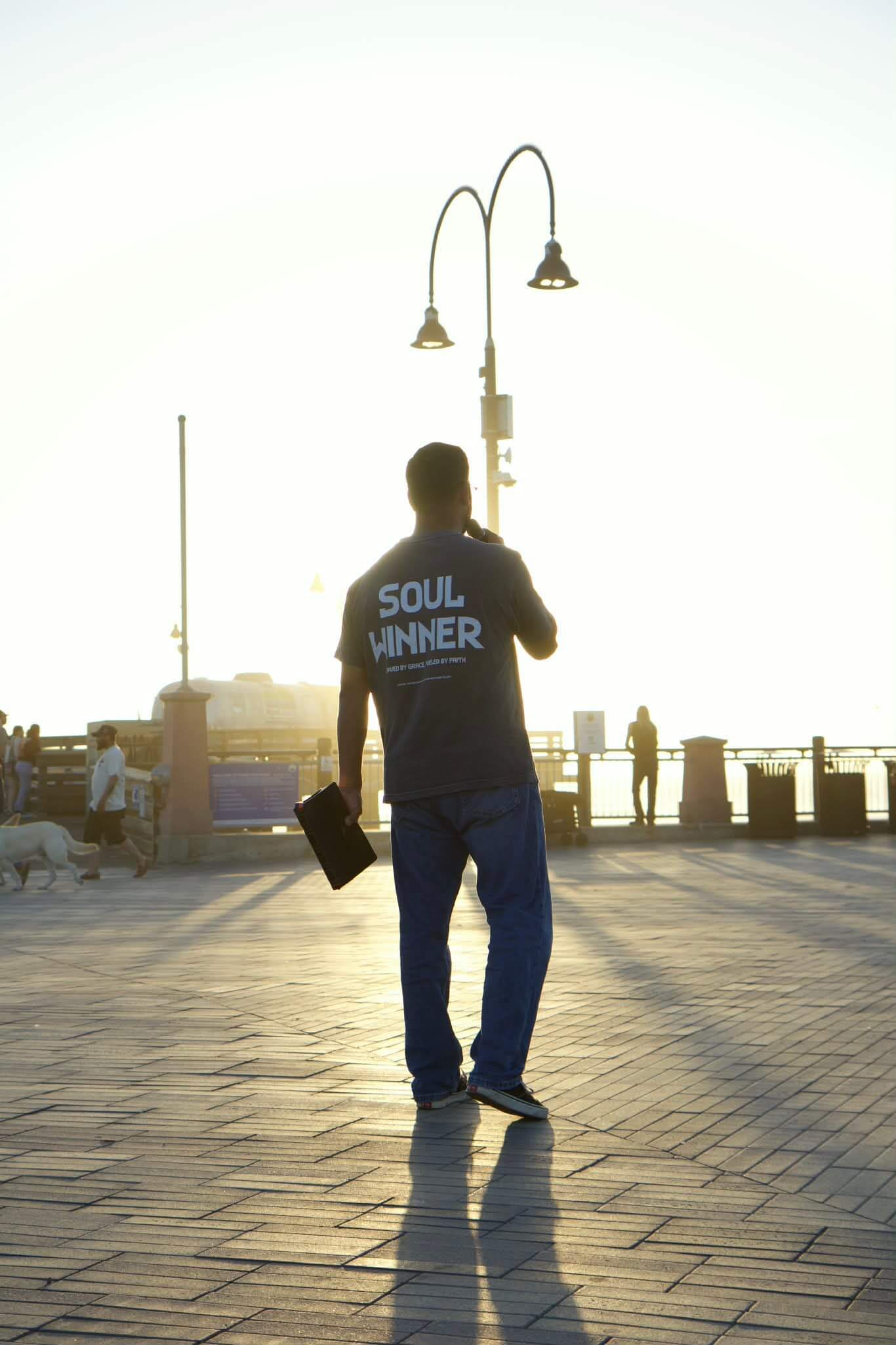 Joshua Maez preaching on a boardwalk at sunset