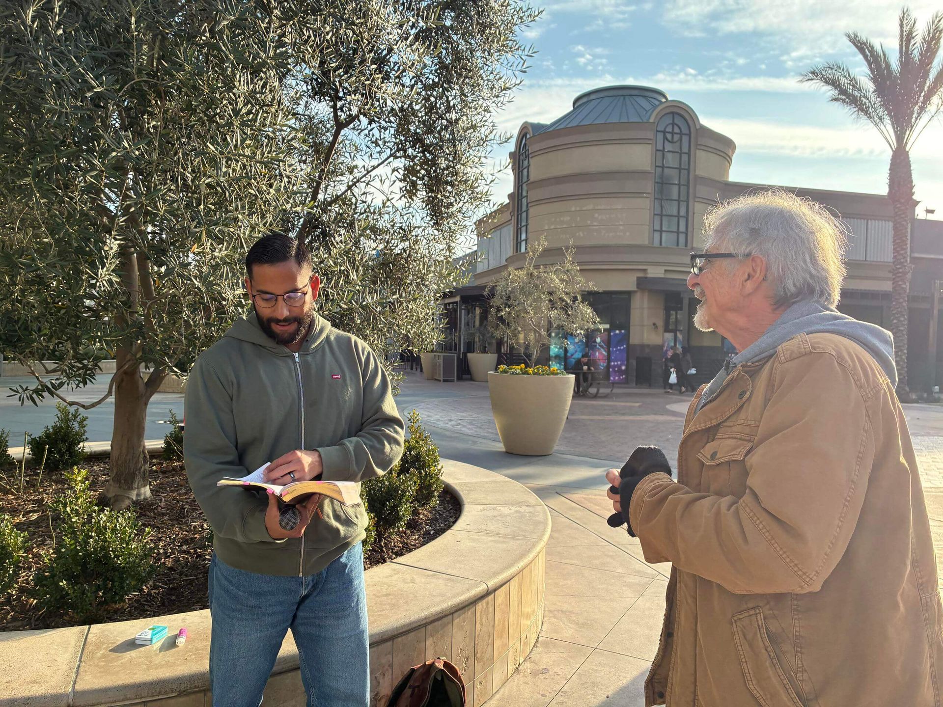 Two men reading the Bible outside a shopping center