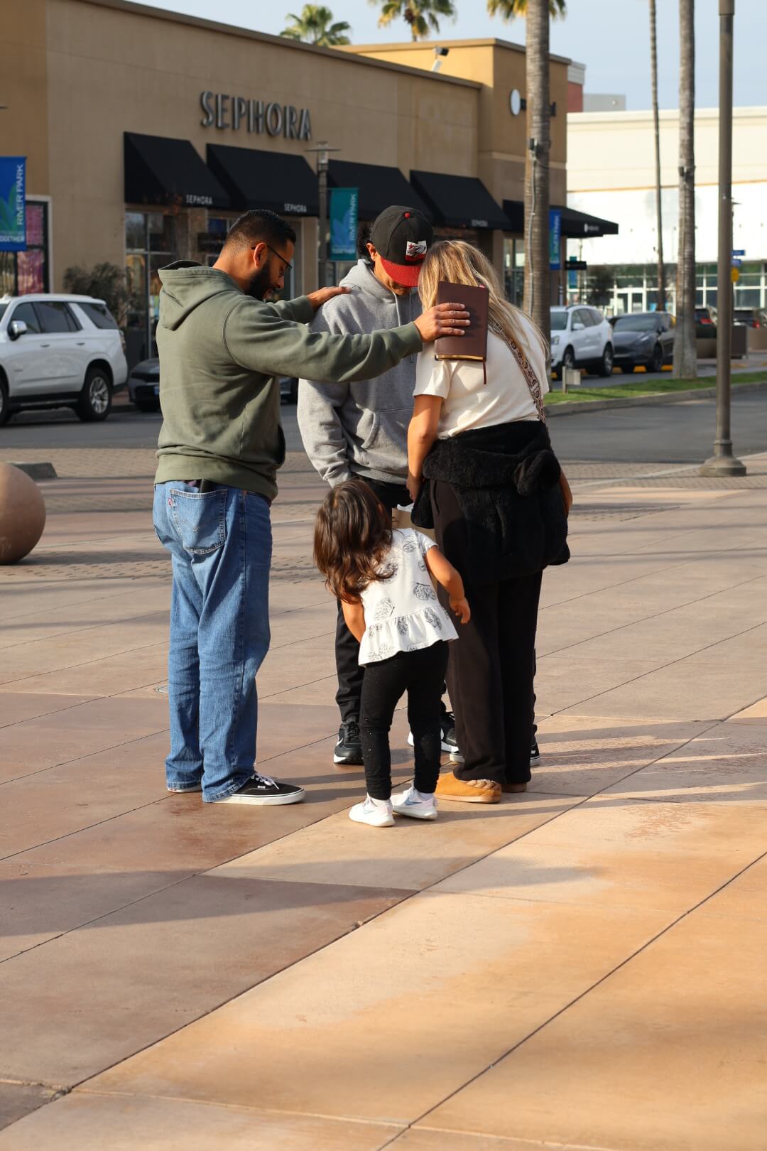 A family praying outside a shopping center
