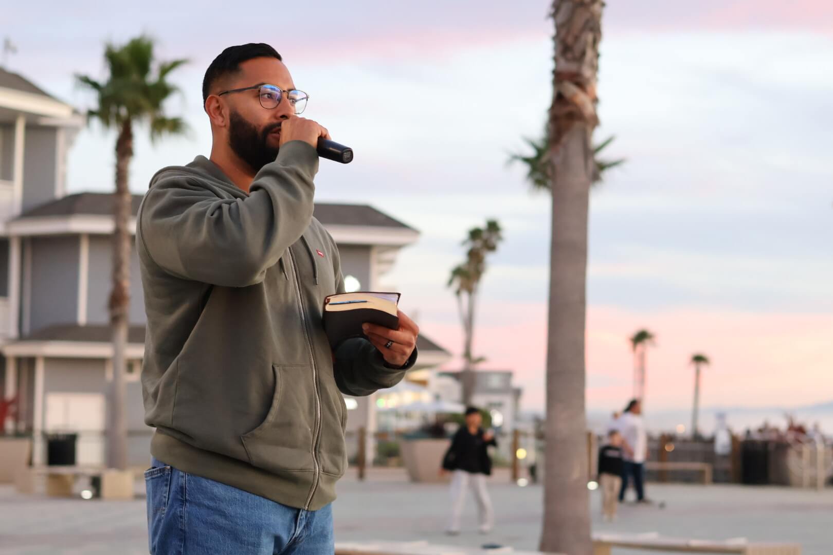 Joshua Maez preaching outdoors with a microphone and his Bible