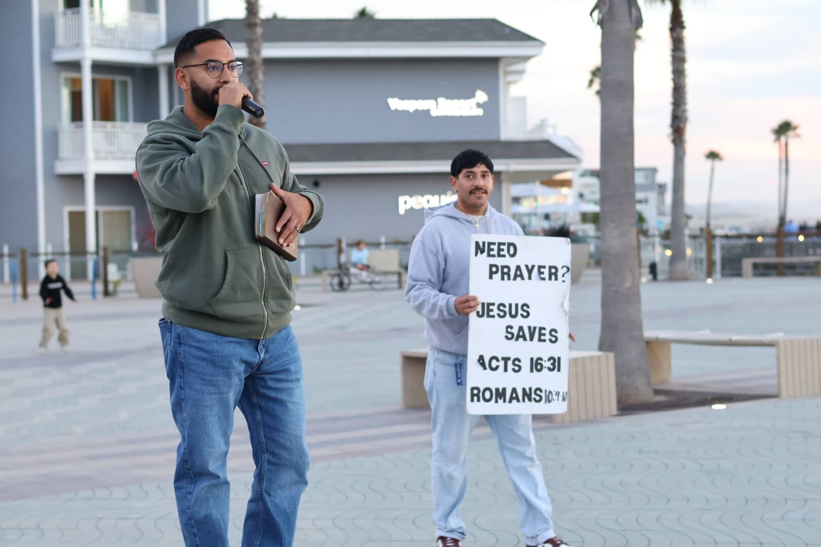 Holding a Need Prayer? sign at the beach
